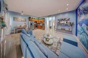 A modern living room with a sofa, coffee table, and a TV wall art. - Tranquility 2Bed/2Bath/2K -5 Star DT Area -Hot Tub (Fort Lauderdale)