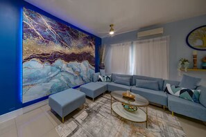 A modern living room with a sectional sofa, a coffee table, and a large abstract painting on the wall. - Tranquility 2Bed/2Bath/2K -5 Star DT Area -Hot Tub (Fort Lauderdale)