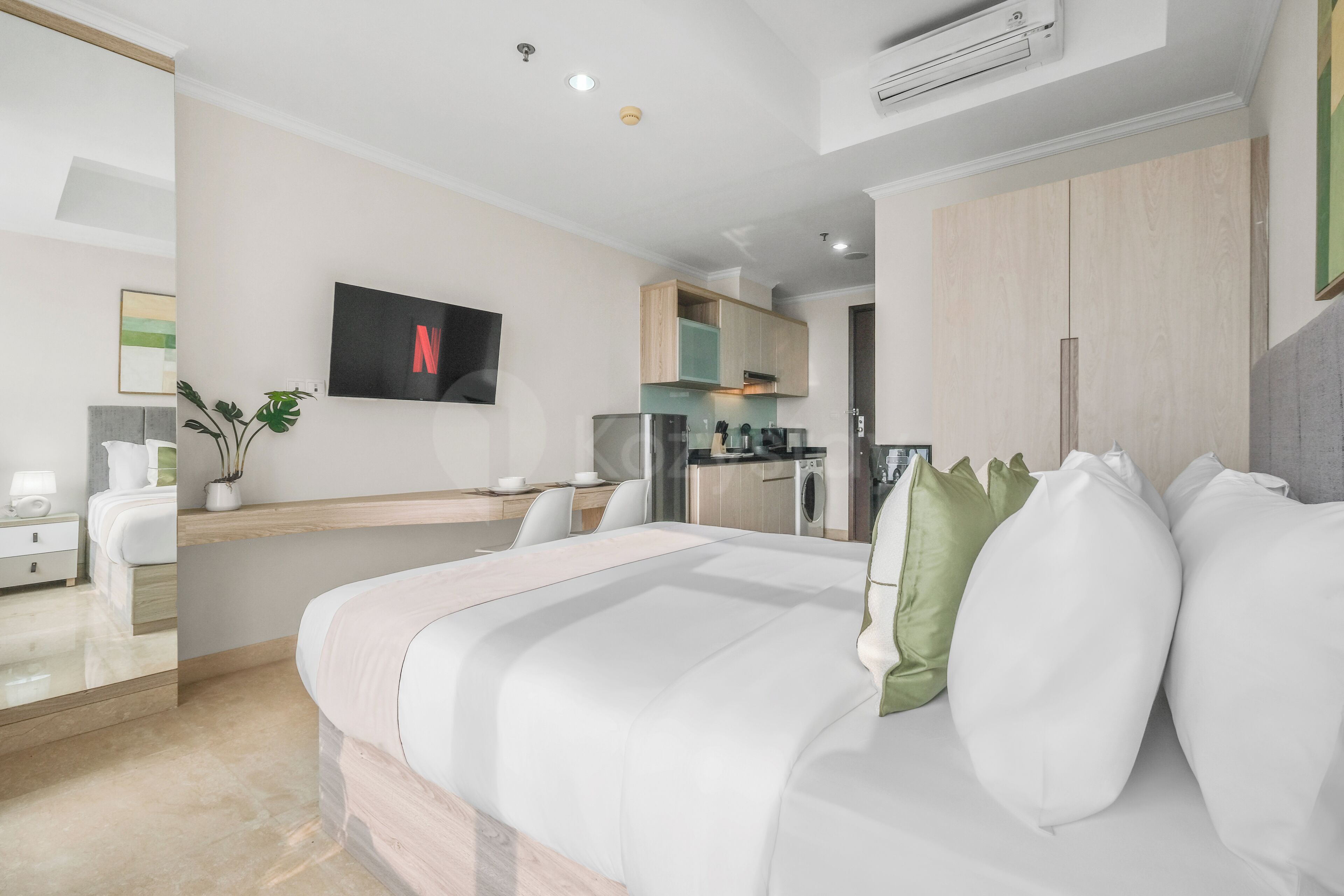 Une chambre d’hôtel moderne équipée d’un lit, d’une télévision, d’une kitchenette et d’une salle de bain.