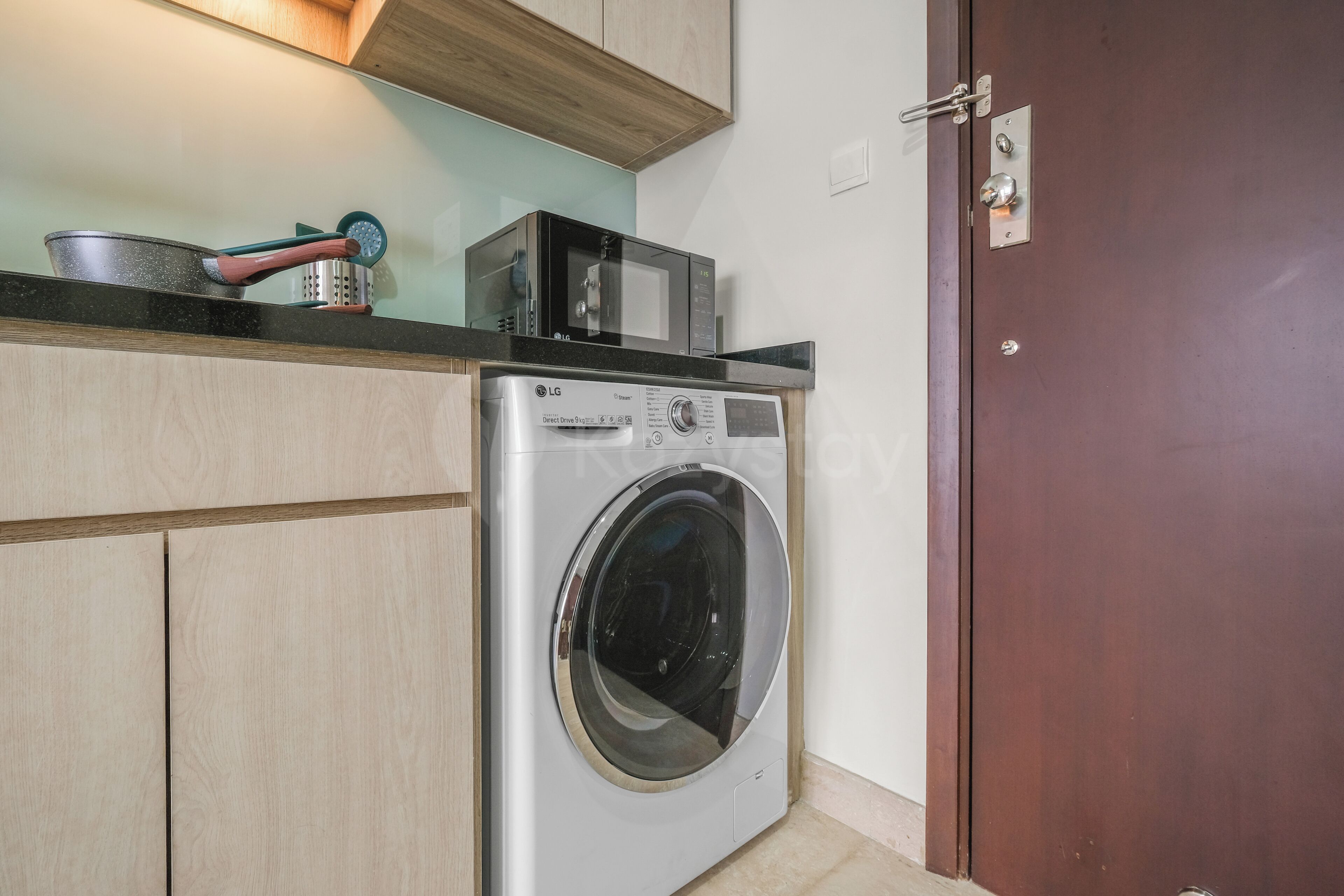 Un espace buanderie compact comprenant un lave-linge, un four à micro-ondes et un petit plan de travail.