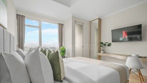 Ein modernes Hotelzimmer mit einem großen Bett, einem Fernseher, einem Schreibtisch und Blick auf die Stadt.
