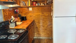 A kitchen with wooden cabinets, a black stove, a white refrigerator, and a wooden countertop. - Uncle Gary’s Wonky Cabin in Steinhatchee, FL (Steinhatchee)