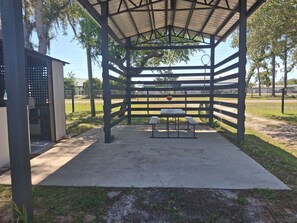 A covered pavilion with picnic tables, a basketball hoop, and a fenced sports field. - Uncle Gary’s Wonky Cabin in Steinhatchee, FL (Steinhatchee)
