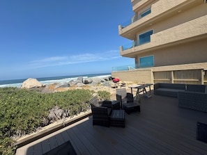 Um terraço com mobiliário de exterior, churrasqueira e vista para o oceano.