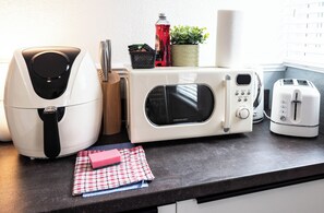 A kitchen with a microwave, toaster, and air fryer on the counter. - The Bay Apart-Hotel by Guestz (Morecambe)