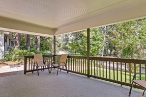 A covered outdoor area with a wooden bench and chairs, surrounded by trees and a view of a residential street. - Delightful 3-bedroom house with AC in charming Decatur (Decatur)