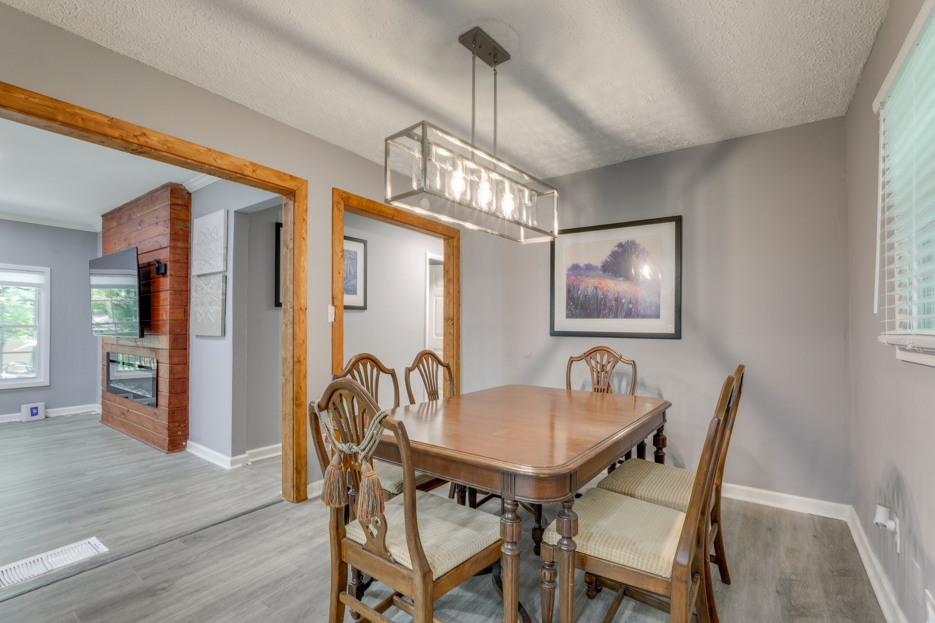 A dining area with a wooden table and chairs, a chandelier, and a fireplace.