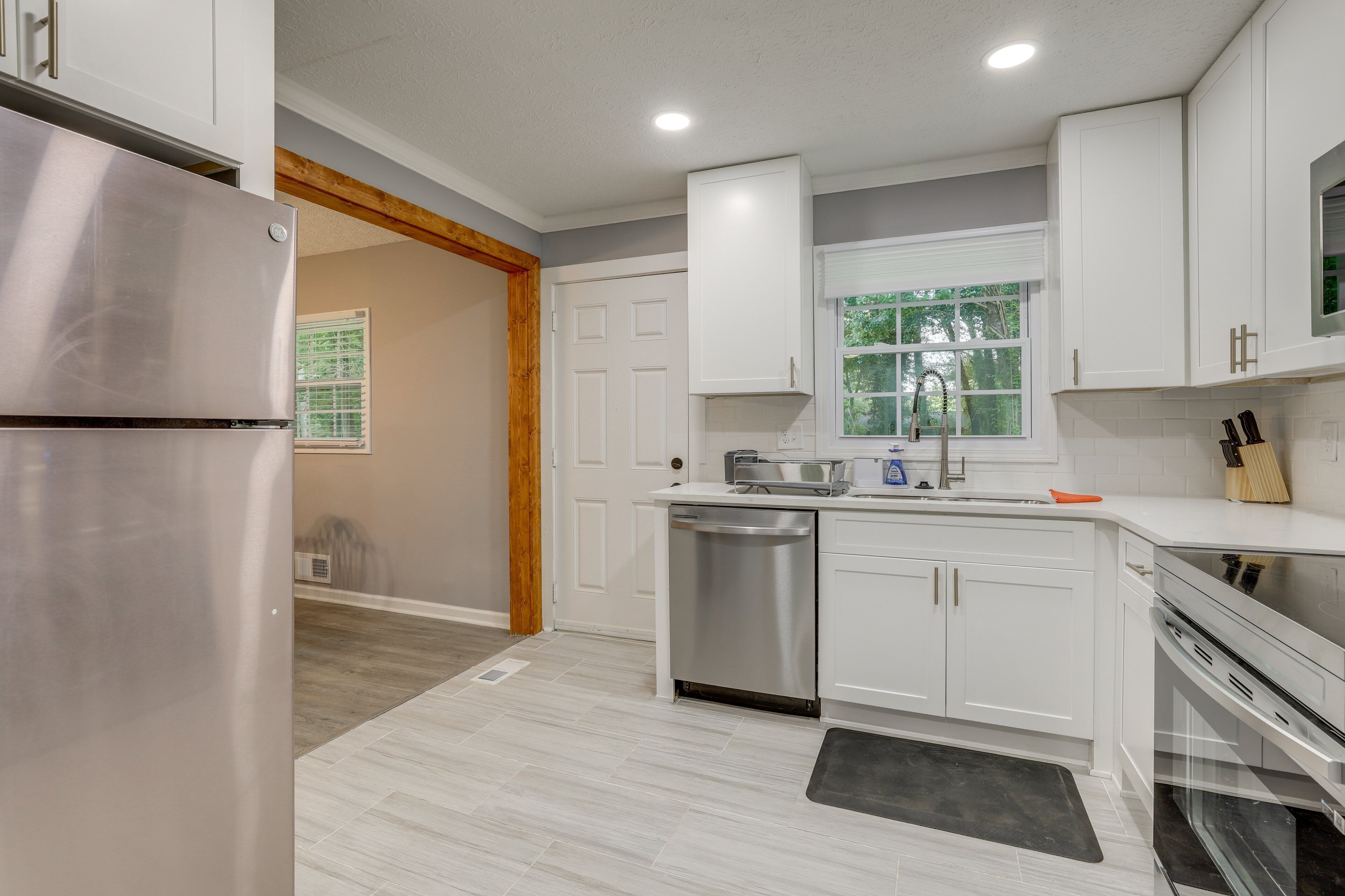 A modern kitchen with white cabinets, stainless steel appliances, and a window providing natural light.