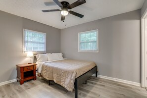 A bedroom with a bed, a nightstand, a ceiling fan, and two windows. - Delightful 3-bedroom house with AC in charming Decatur (Decatur)