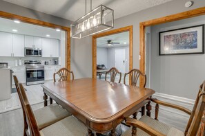 A dining area with a wooden table and chairs, a kitchen with modern appliances, and a framed picture on the wall. - Delightful 3-bedroom house with AC in charming Decatur (Decatur)