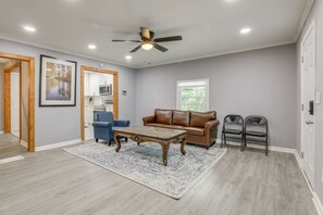 A spacious living room with a ceiling fan, a brown leather sofa, a blue armchair, and a coffee table. - Delightful 3-bedroom house with AC in charming Decatur (Decatur)