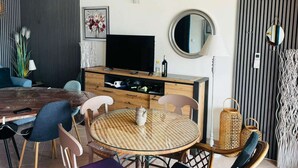 Moderni olohuone, jossa on televisio, ruokapöytä, tuoleja ja sohva.