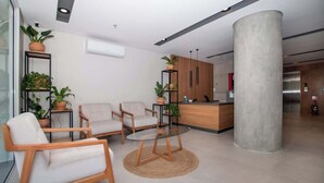 A modern lobby with a reception desk, seating area, and potted plants. - Corporate Stays First Living - 403 (Asunción)