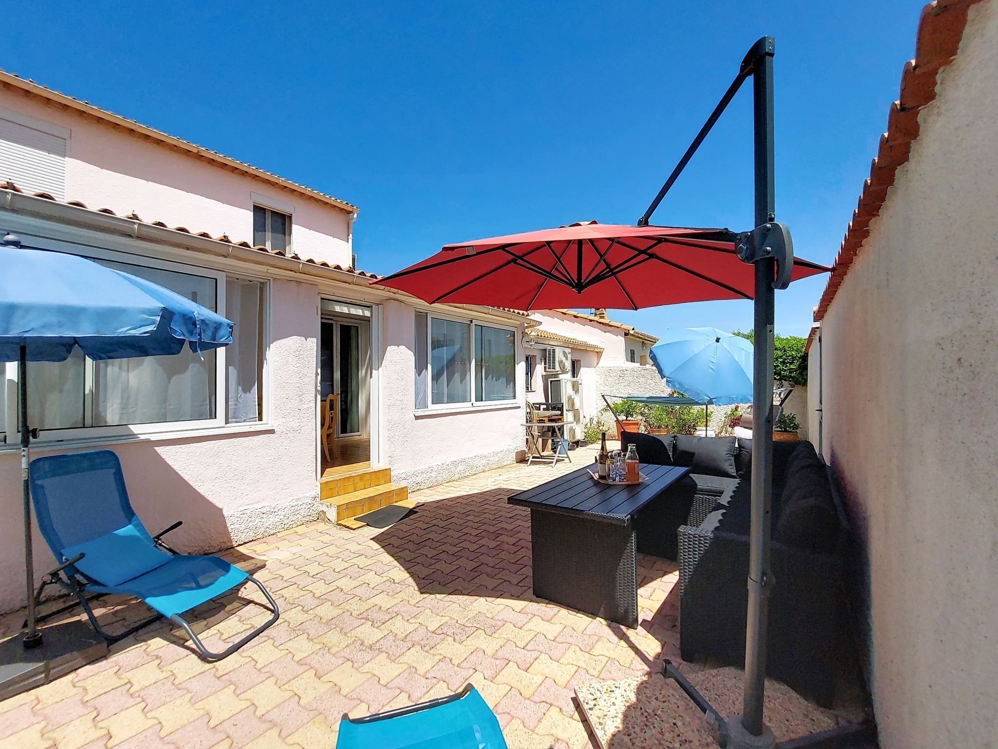 A patio with a table, chairs, and umbrellas.