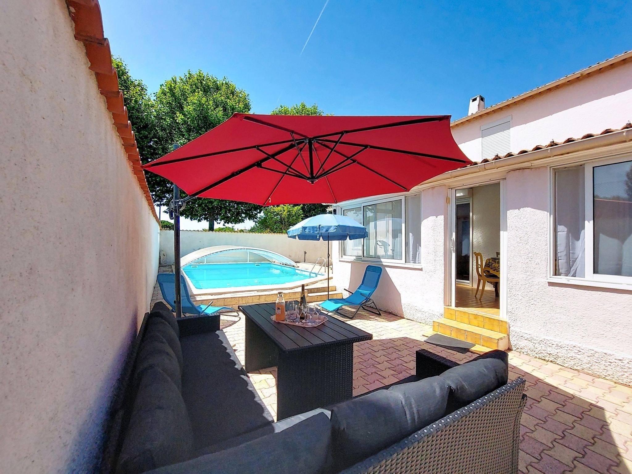 A pool area with a hot tub, outdoor furniture, and a red umbrella.
