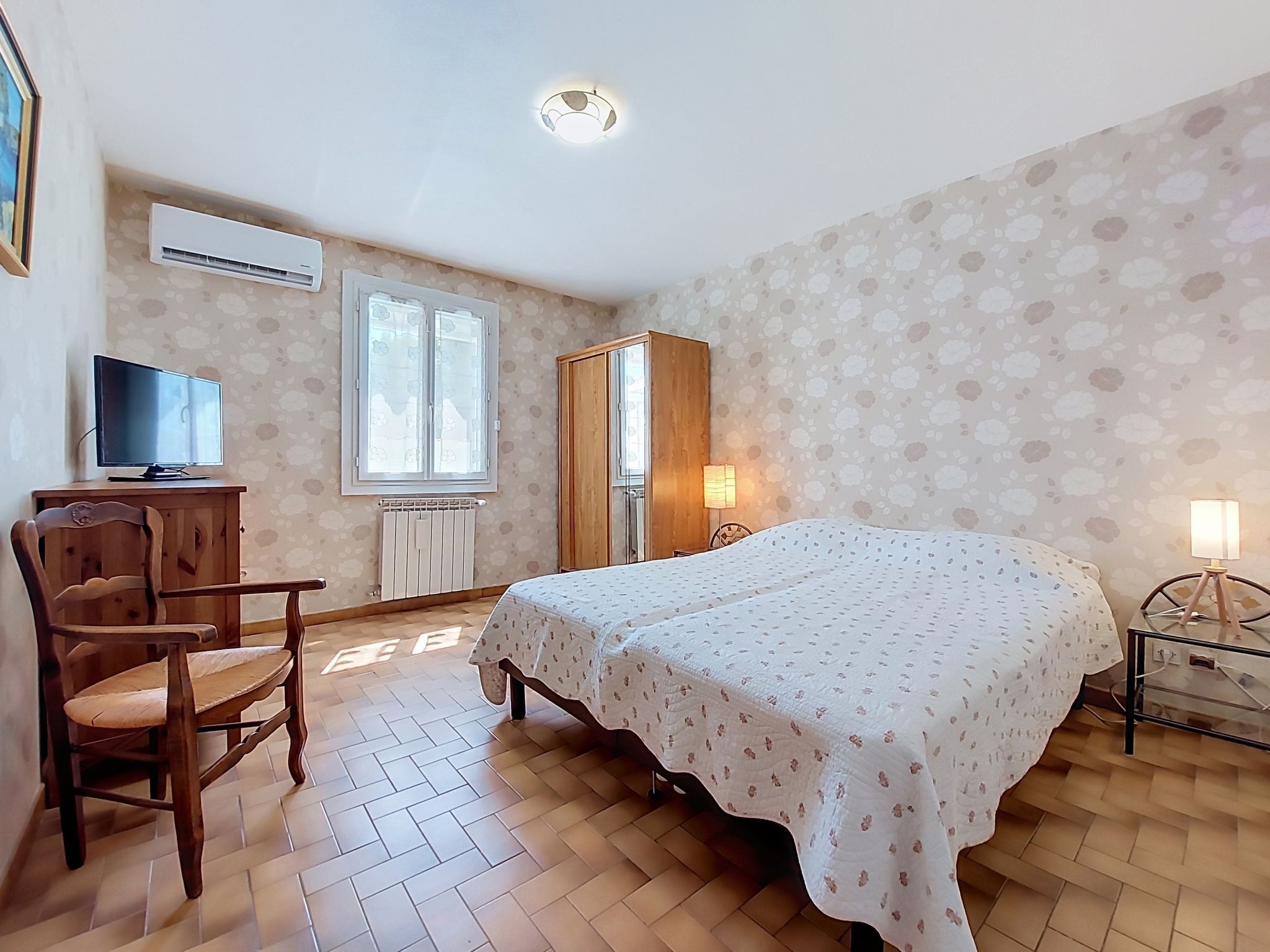 A bedroom with a bed, a chair, a desk, a wardrobe, and a window.