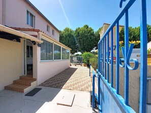 A narrow alleyway with a building on one side and a blue metal fence on the other. - L Escapade Orangeoise by Interhome (Orange)