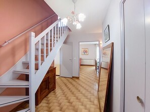 A staircase with white railings leading to a landing, a wooden floor, and a ceiling light fixture. - L Escapade Orangeoise by Interhome (Orange)