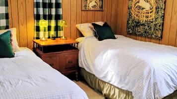 Un dormitorio con dos camas, una mesita de noche, una lámpara y una pared con un espejo decorativo y obras de arte.