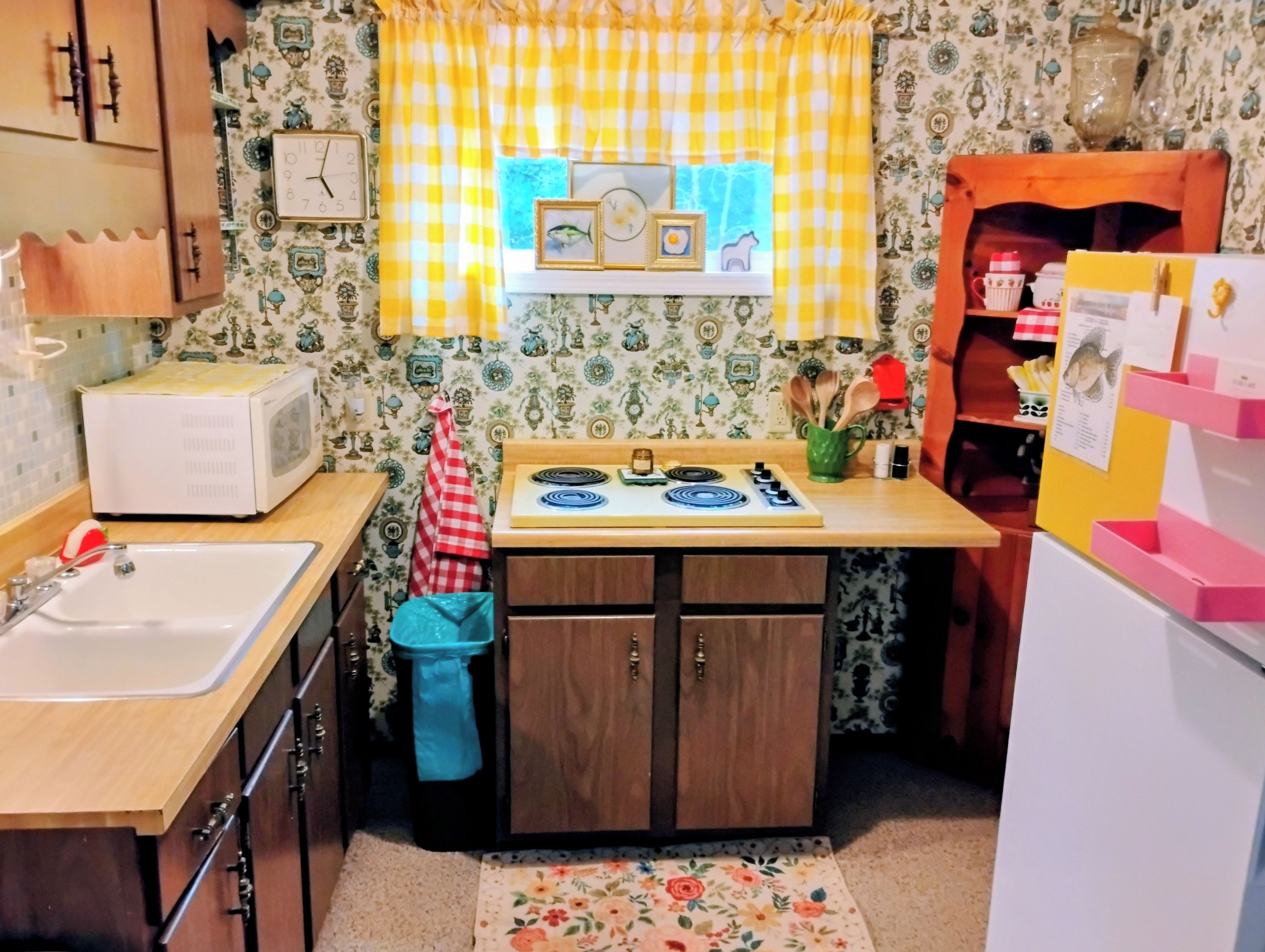 Una cucina con microonde, fornello, lavello e mobili in legno.