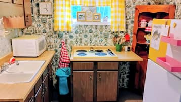Una cucina con microonde, fornello, lavello e mobili in legno.