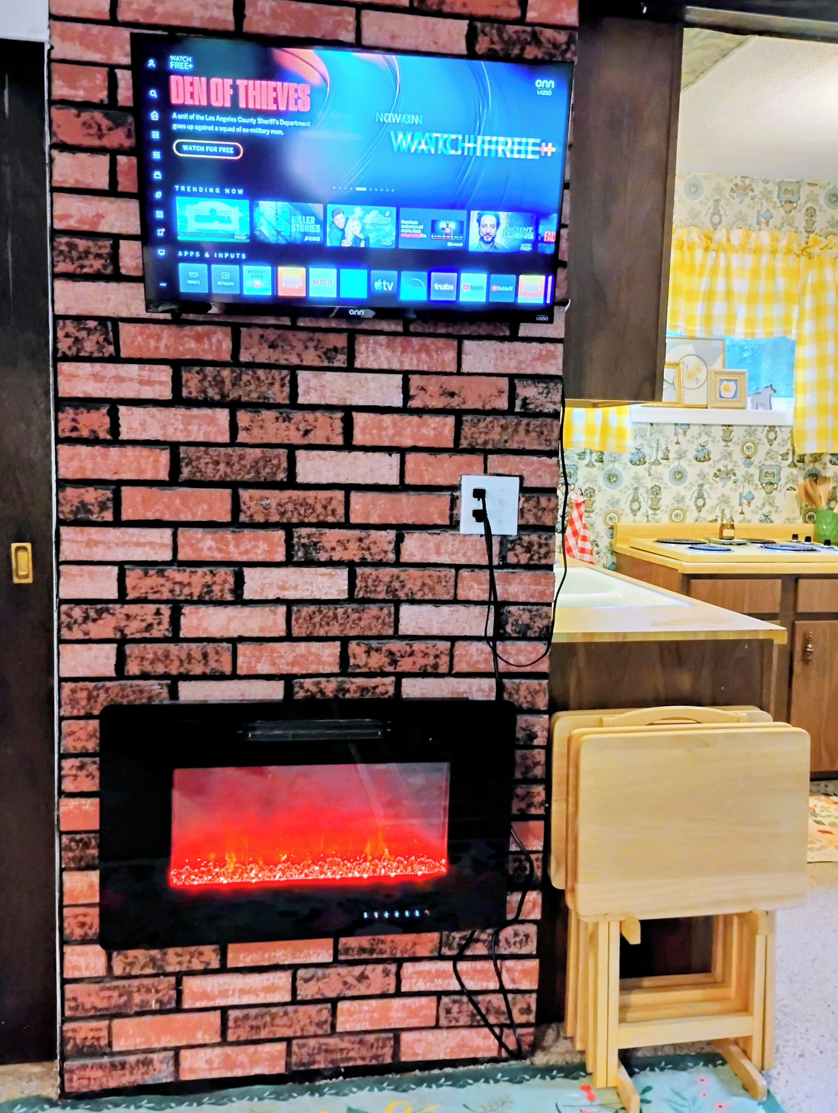A television mounted on a brick wall with a fireplace below.