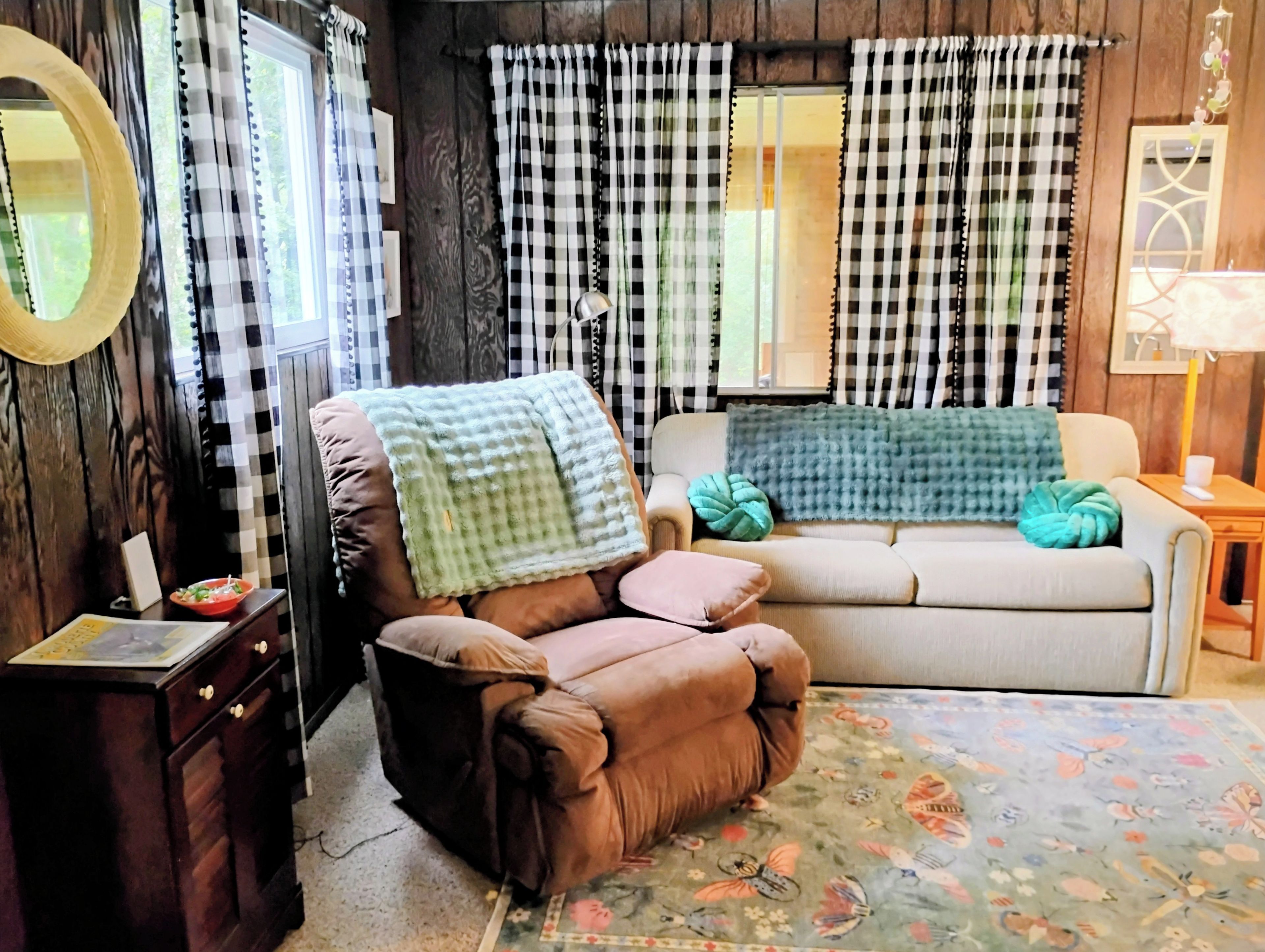 Uma sala de estar acolhedora com um sofá marrom, um sofá bege e um tapete estampado.