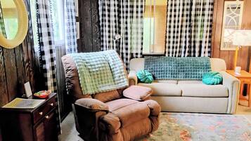 Uma sala de estar acolhedora com um sofá marrom, um sofá bege e um tapete estampado.