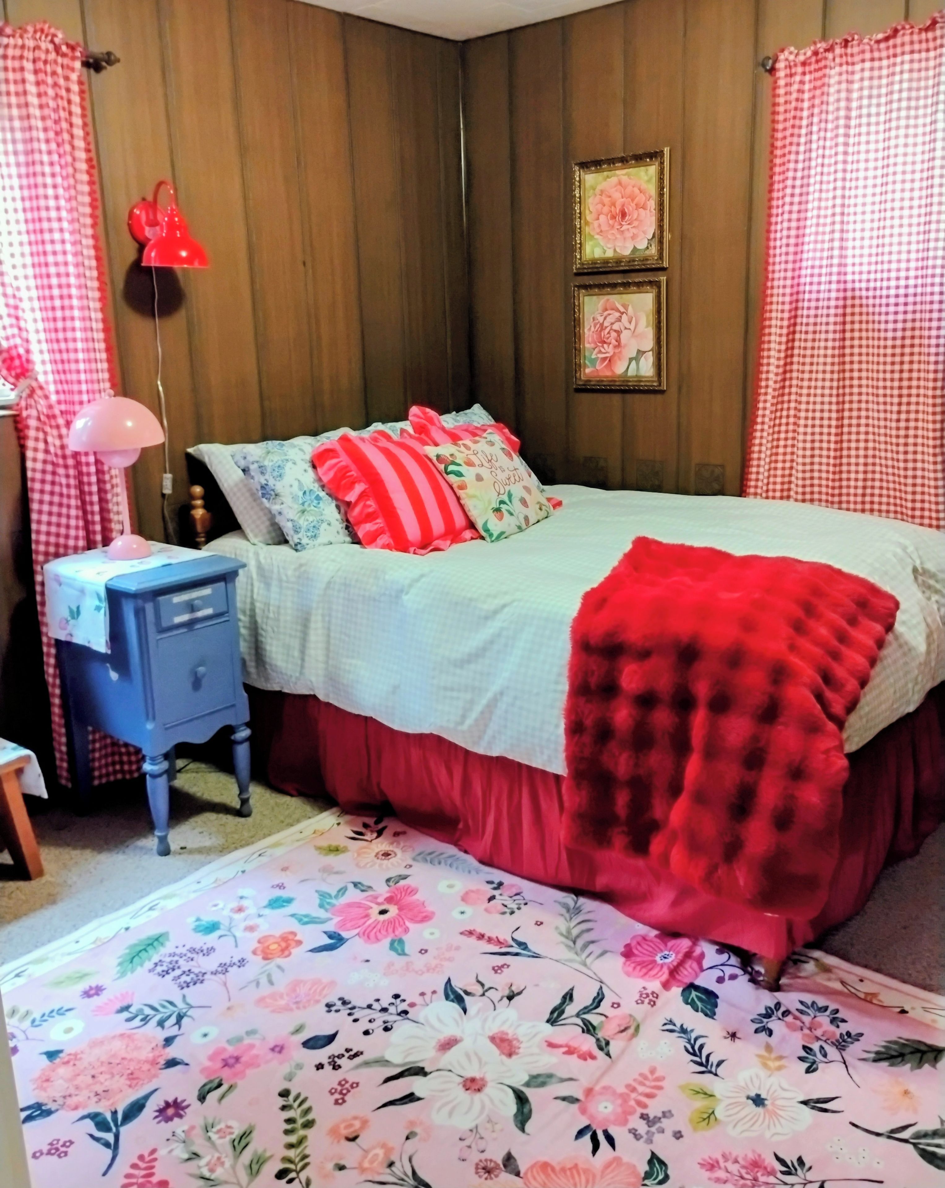 Quarto com cama, mesa de cabeceira, abajur e tapete estampado.
