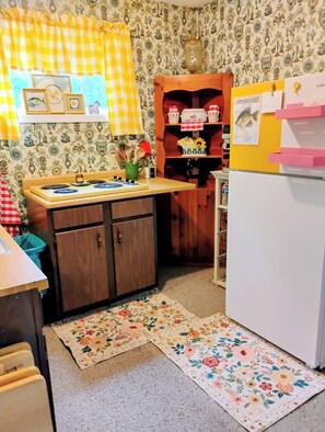 Eine Küche mit einem Holsschrank, einem weißen Kühlschrank und einer Wandfliesenverkleidung mit Muster.