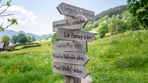 Een houten bord met richtingaanduidingen, met verschillende pijlen die naar verschillende bestemmingen en afstanden in kilometers wijzen.