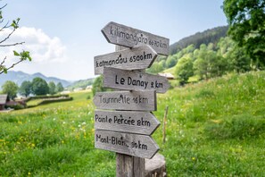 A wooden directional signpost with multiple arrows pointing to various destinations and distances in kilometers. - Ravoux : Chalet, terrasse  et  vue montagne (LA CLUSAZ)