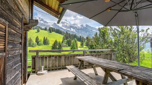 Een houten terras met picknicktafels met uitzicht op een bergachtig landschap.