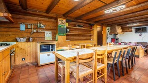 Een rustiek houten interieur met een eethoek, keuken en een open haard.