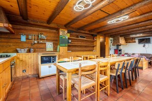 A rustic wooden interior with a dining area, kitchen, and a fireplace. - Ravoux : Chalet, terrasse  et  vue montagne (LA CLUSAZ)