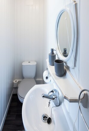 A modern bathroom with a toilet, sink, and mirror. - The Bay Apart-Hotel by Guestz (Morecambe)