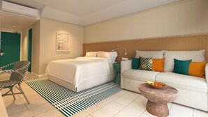 Habitación de hotel con cama, sofá, sillón, una mesita con fruta y un tapete estampado.