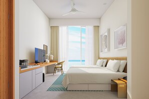 A hotel room with a bed, a desk, a chair, a TV, and a view of the ocean.