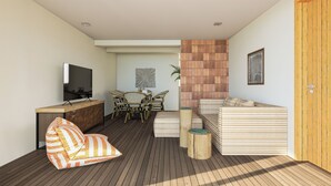 Una sala de estar moderna con suelo de madera, un sofá, un televisor, una zona de comedor con sillas y una puerta de madera.