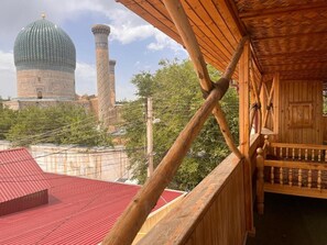 A wooden balcony with a view of a mosque with a dome and minaret. - EmirA (Samarkand)