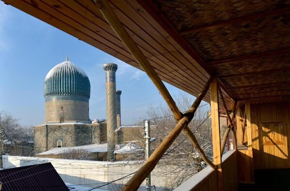 A view of a building with a dome and a tall minaret, a wooden structure with a sloped roof, and a solar panel on the roof. - EmirA (Samarkand)