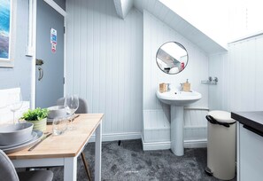 A compact kitchen with a sink, mirror, and trash bin. - The Bay Apart-Hotel by Guestz (Morecambe)