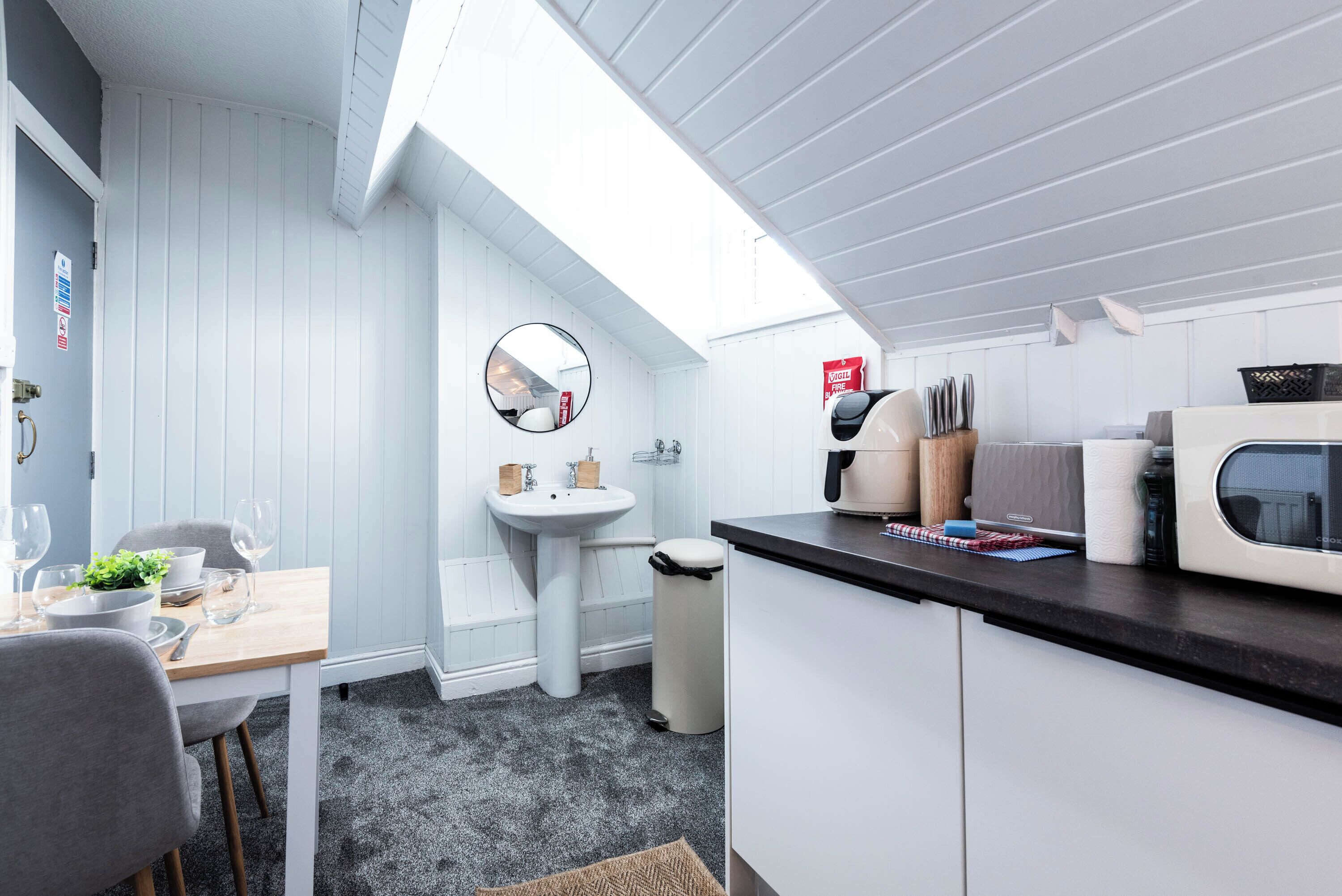 A compact kitchen with a sink, a microwave, and a dining area with a table and chairs.