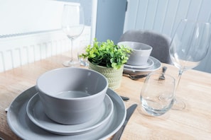 A dining table with a bowl, plates, cutlery, and a small potted plant. - The Bay Apart-Hotel by Guestz (Morecambe)
