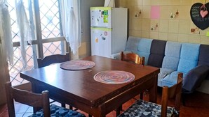 A dining area with a wooden table, two woven placemats, and a blue and grey sofa. - The Rainbow House (Roma)