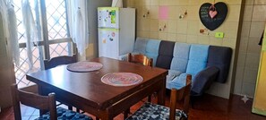 Ein Essbereich mit einem Holztisch, zwei gewebten Platzsets und einem blau-grauen Sofa.