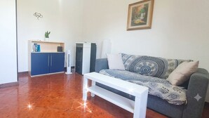 A living room with a sofa, a white bench, a blue cabinet, and a wall-mounted air conditioner. - The Rainbow House (Roma)