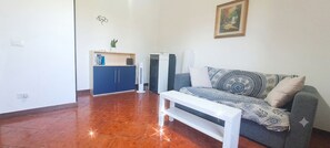 Ein Wohnzimmer mit einer Couch, einer weißen Bank, einem blauen Schrank und einer Wandklimaanlage.