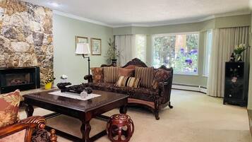 A living room with a stone wall, a fireplace, a sofa, a coffee table, and a view of the outdoors.