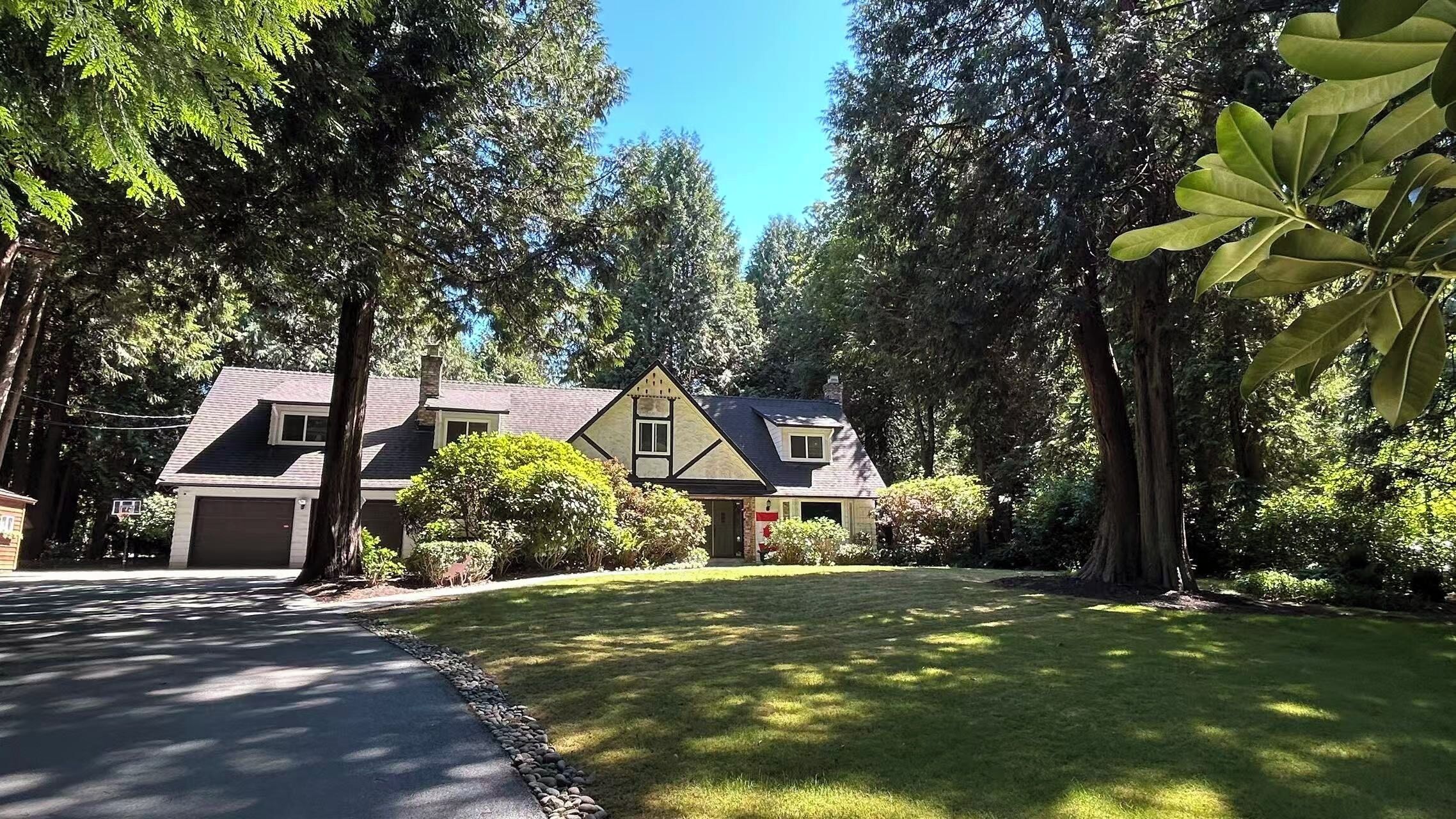 Uma casa de dois andares com garagem, cercada por árvores e um gramado bem cuidado.
